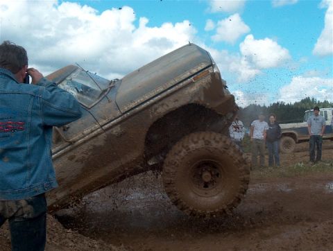 1979 Ford Bronco - A truck is stuck in the mud during an off-road event, with spectators observing the action.