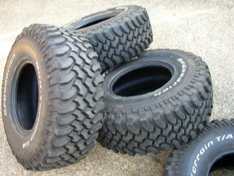 1995 Ford Bronco - A collection of BFGoodrich Mud-Terrain T/A tires, known for their aggressive tread pattern, are displayed on a rough surface.