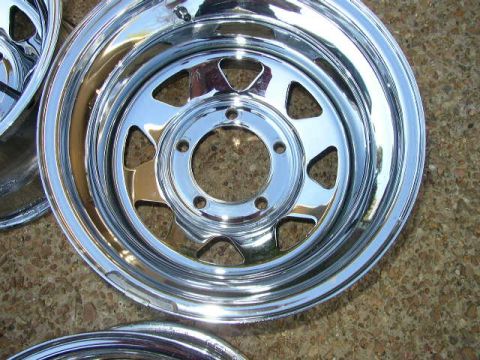 1995 Ford Bronco - Chrome wheel rim shown in detail, a five-lug bolt pattern and triangular openings.