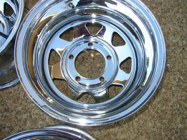 Close-up of a chrome wheel rim with triangular cutouts and a five-lug bolt pattern