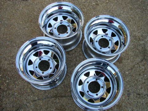 1995 Ford Bronco - A set of four chrome wheels, likely aftermarket, are displayed on a rough ground surface.