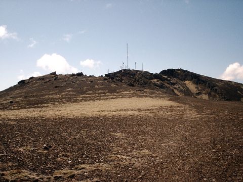 1996 Ford Bronco - A barren mountain slope dotted with sparse vegetation leads to a rocky summit topped with numerous radio towers and antennas.