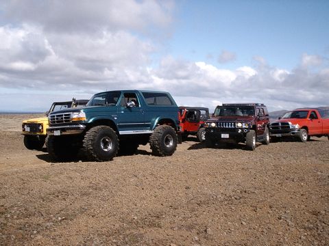 1996 Ford Bronco - A 1996 Ford Bronco leads a group of off-road vehicles on a dirt terrain.