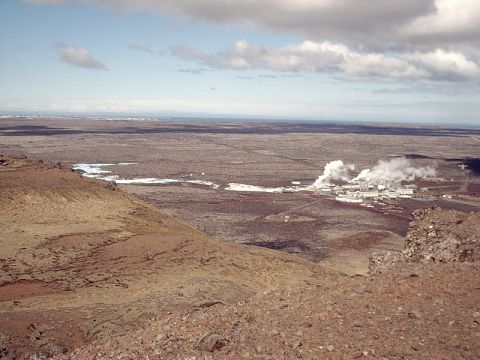 1996 Ford Bronco - A geothermal power plant releases steam into the sky, set against a backdrop of a desolate, rocky terrain and a distant city.