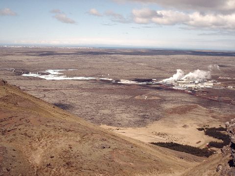 1996 Ford Bronco - An expansive view of a geothermal power plant releasing steam into the atmosphere, set against a desolate, rocky terrain.