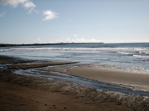 1996 Ford Bronco - A wide view of a beach shows intricate water channels carved into the sand leading to the ocean under a partly cloudy sky.