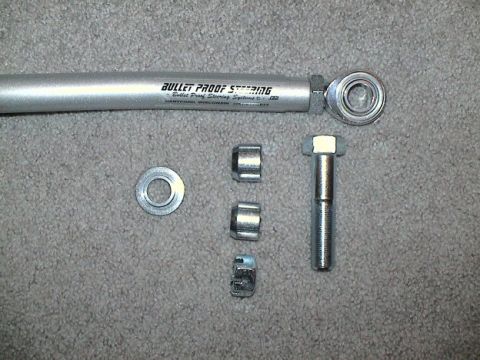 1979 Ford Bronco - A steering linkage rod and its associated hardware are laid out on a carpeted surface.