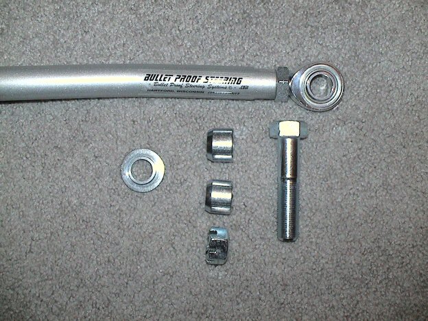 Bullet Proof Steering heim-joint link with spacers, washer and bolt laid out on carpet