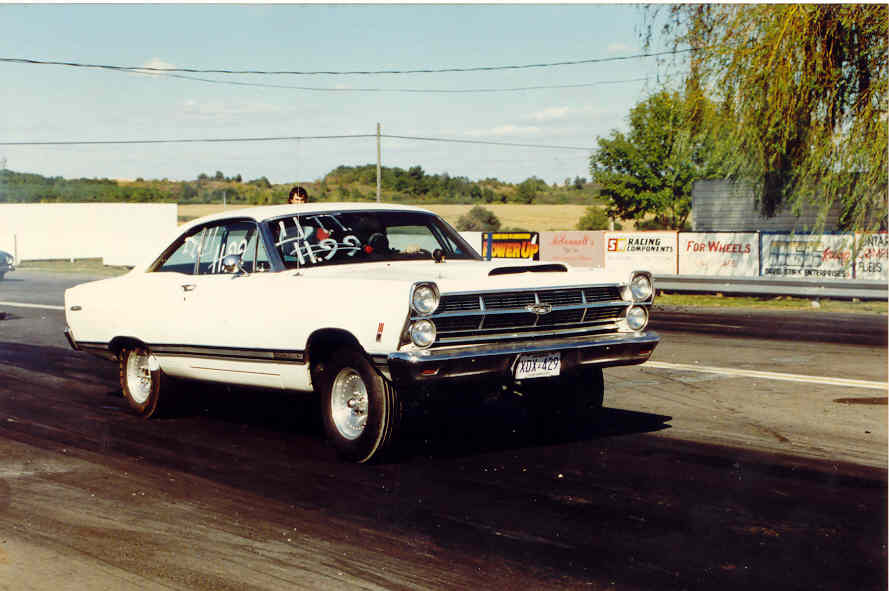 White Ford Fairlane hardtop with drag slicks staged at a drag strip