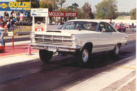 1967 Ford Fairlane - A 1967 Ford Fairlane launches off the line at a drag strip, its front wheels lifting off the pavement.