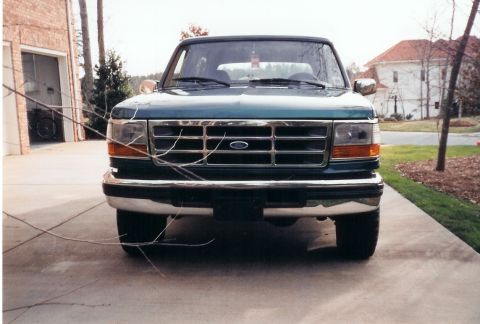 1996 Ford Bronco - This Ford truck is parked in a driveway with a garage and house in the background.