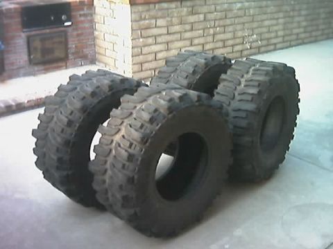 1985 Ford Bronco - A group of four off-road tires are displayed on a concrete surface.