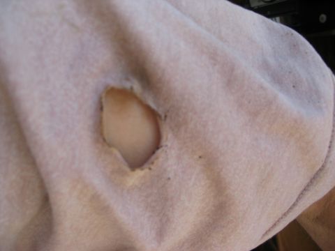 1986 Ford Bronco - A close-up view of damaged fabric, showing a tear with a hole.