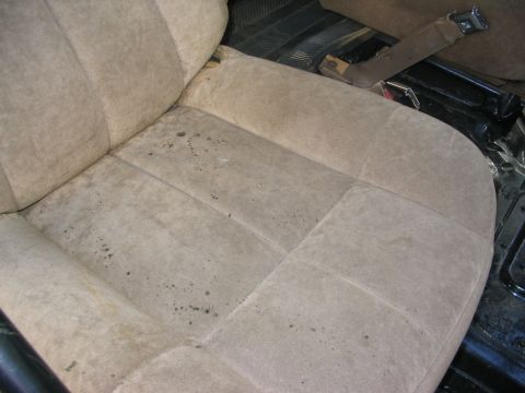 1986 Ford Bronco - Interior view of a worn car seat, showing stains and fabric damage.