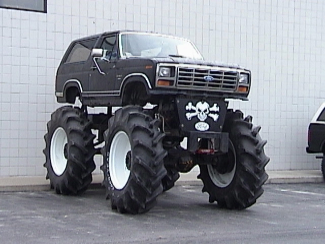 Lifted black Ford Bronco on huge tractor tires with skull graphic, front 3/4 view