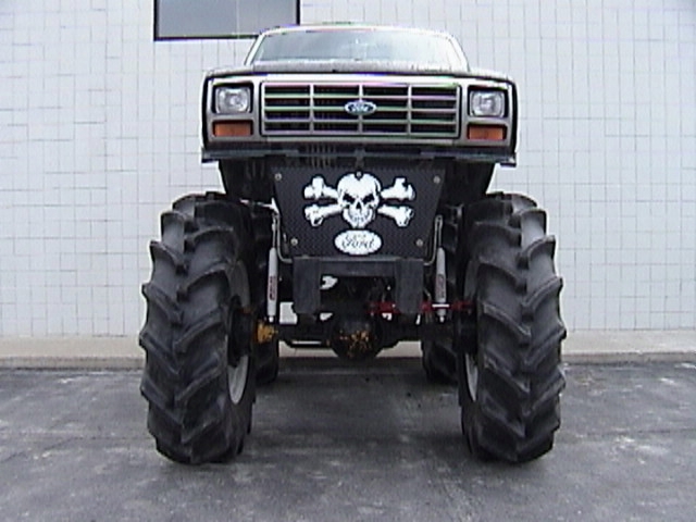 Lifted black Ford SUV on huge tractor tires, front view with skull graphic