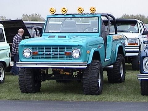 1995 Ford Bronco - This teal Ford Bronco has a lifted suspension and large off-road tires, with smiley face lights on its roof.