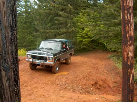 1978 Ford Bronco - A black 1978 Ford Bronco navigates a muddy, wooded trail.