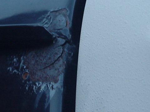 1993 Ford Bronco - Detail of significant rust damage on a vehicle's metal panel.