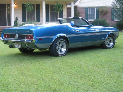 1973 Ford Mustang - A blue 1973 Ford Mustang convertible sits on a lawn, showing its side and rear details.