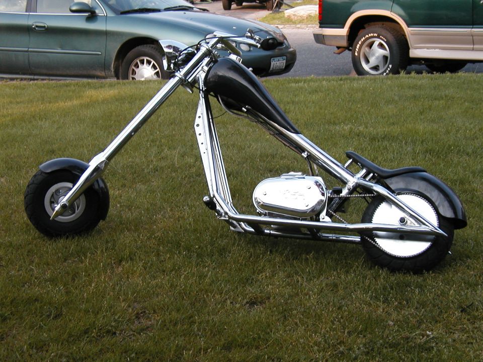 Chopper motorcycle with chrome frame, black tank, and black seat on grass