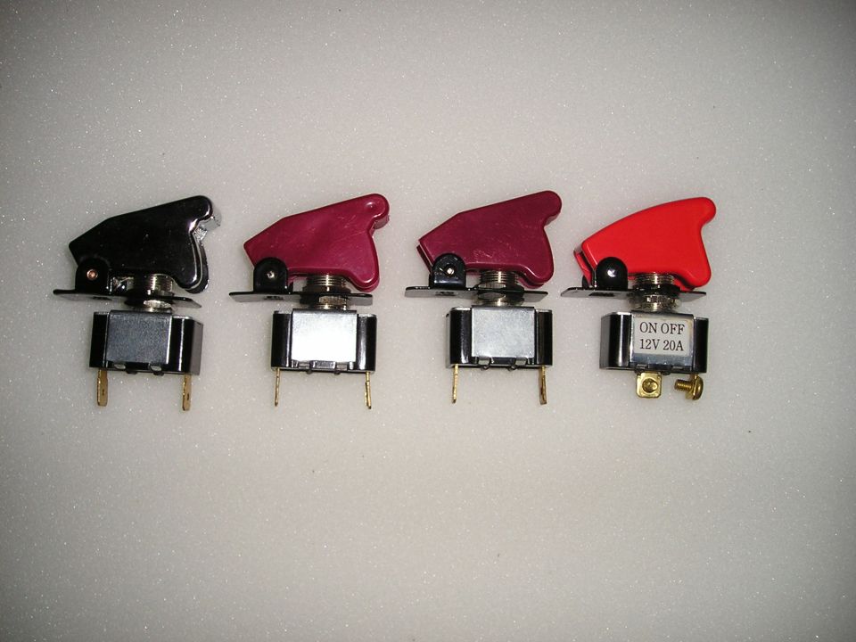 Four toggle switches with flip-up safety covers in black, pink and red