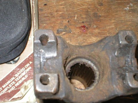 1978 Ford Bronco - A close-up view of a rusty driveshaft yoke, showing its splined interior and mounting holes.