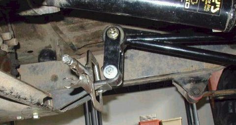 1974 Ford Bronco - A close-up view of vehicle undercarriage components, with a C-clamp affixed to a metal bracket.