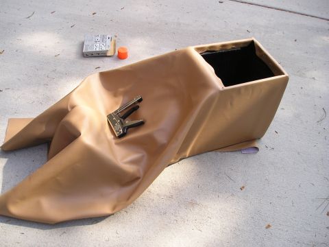1996 Ford Bronco - A custom center console is being reupholstered with tan vinyl, with a stapler and a small orange cap nearby.