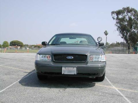 2000 Ford Crown Victoria - A 2000 Ford Crown Victoria is parked in an asphalt lot under a clear sky.