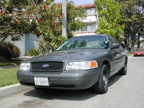 2000 Ford Crown Victoria - A gray 2000 Ford Crown Victoria is parked on a residential street.