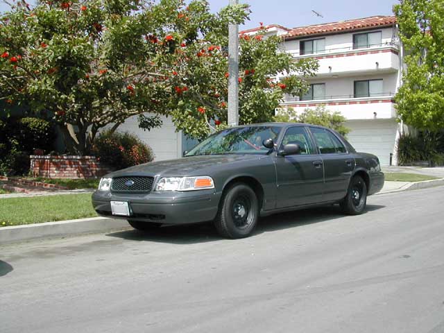 Dark gray 2000 Ford Crown Victoria sedan parked on street, front 3/4 view