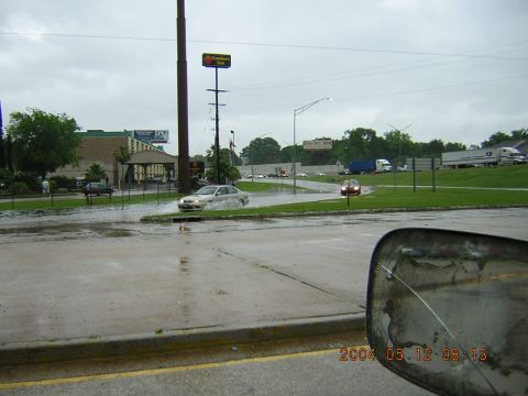 1984 Chevrolet Blazer - A silver sedan navigates through flooded streets under a cloudy sky, with other vehicles visible in the background.