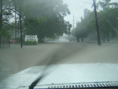 1984 Chevrolet Blazer - A flooded street with a white car in the distance and a red car on the left, under a cloudy sky.