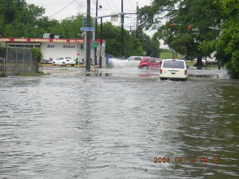 1984 Chevrolet Blazer - Multiple vehicles navigate a flooded street with a motorcycle shop in the background.