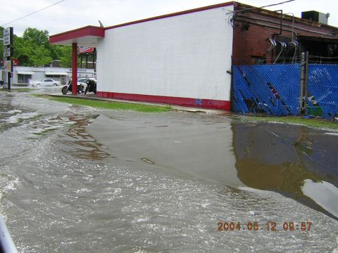 1984 Chevrolet Blazer - A flooded street scene shows a white sedan and two motorcycles parked near a building with a red and white awning.