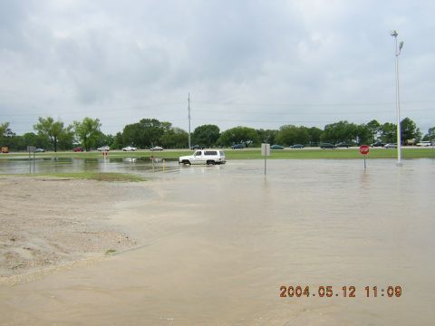 1984 Chevrolet Blazer - A white SUV navigates through a flooded area with other vehicles visible in the distance under a cloudy sky.