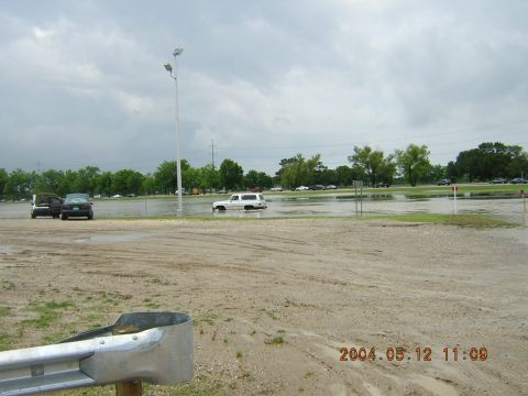 1984 Chevrolet Blazer - A white SUV drives through flooded terrain, with other vehicles visible in the background under a cloudy sky.