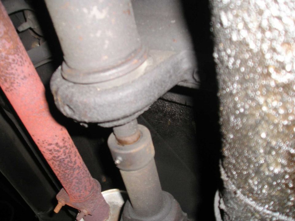 Driveshaft and rusted exhaust pipe under a vehicle