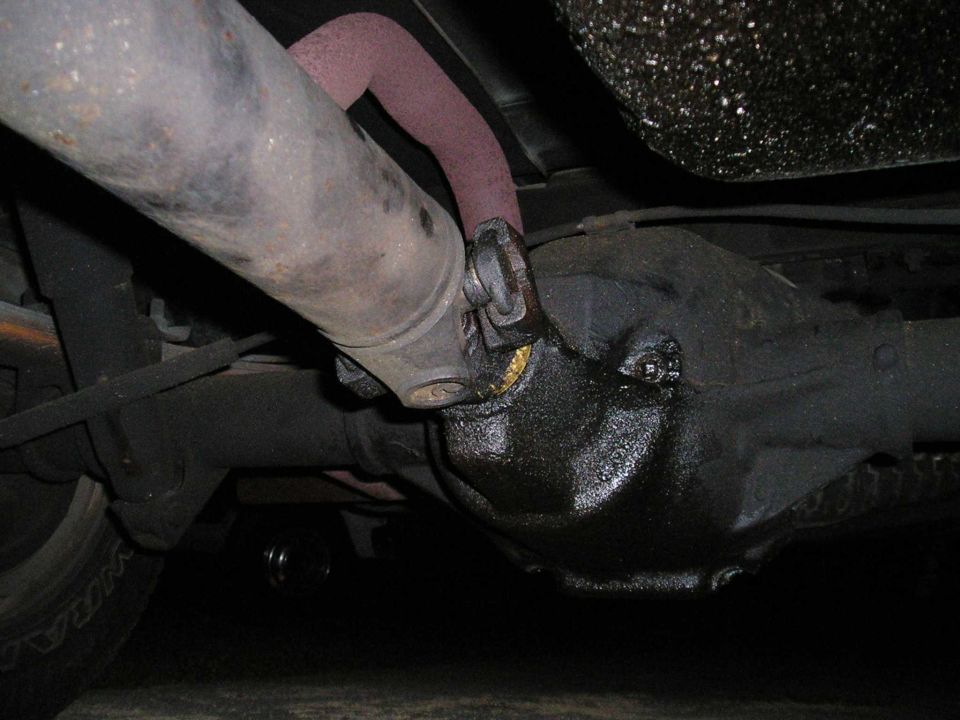 close-up of driveshaft connected to rear differential, exhaust pipe visible