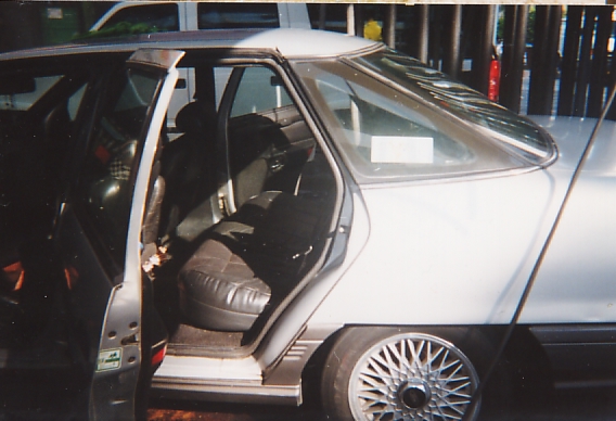 Silver sedan with rear door open showing gray interior and alloy wheels