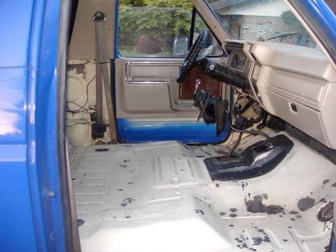 1980 Ford Bronco - The interior of a 1980 Ford Bronco is shown with its floor stripped bare and the dashboard visible.
