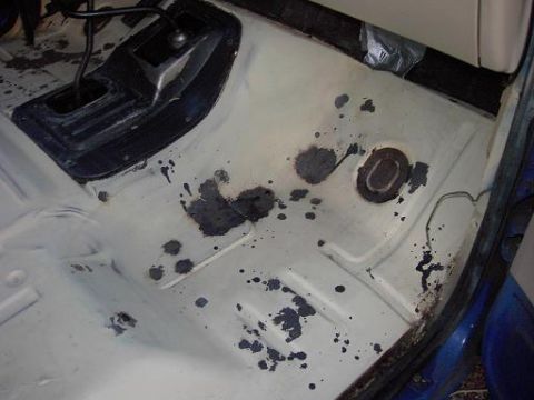 1980 Ford Bronco - The interior floor of a vehicle shows a manual transmission shifter and dark stains on the painted surface.