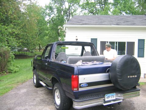 1994 Ford Bronco - A blue Ford Bronco with its top removed is parked in a driveway.