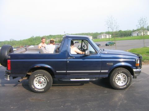 1994 Ford Bronco - Side view of a blue 1994 Ford Bronco with its top removed, carrying passengers.