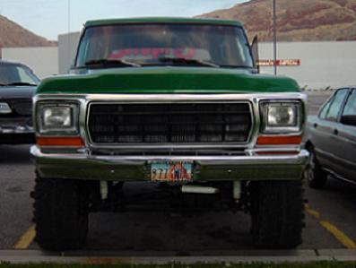 1979 Ford Bronco - This green 1979 Ford Bronco features a lifted suspension and prominent off-road tires, seen from a direct front-facing perspective.
