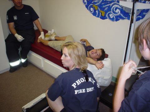1990 Ford Bronco - Firefighters are seen attending to a patient lying on a medical cot in what appears to be a clinic or station.