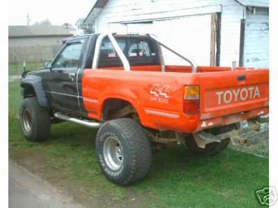 1986 Ford F-150 - This Toyota pickup truck has a two-tone paint scheme and is modified with a lift kit and off-road tires.