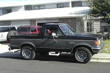 1989 Ford Bronco - This 1987 Ford Bronco is parked in front of a building. A second vehicle is visible behind it.