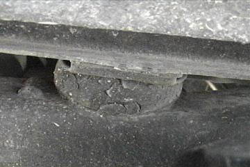 1989 Ford Bronco - This photo shows a close-up of a vehicle's suspension system, specifically a rubber component that appears to be in poor condition.